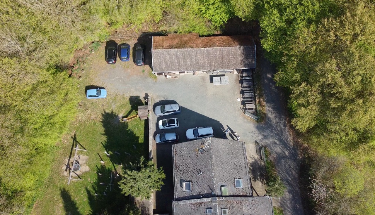 Drohnenblick auf Parkplatz, Innenhof und Spielbereich des Freizeitheims Forsthaus.