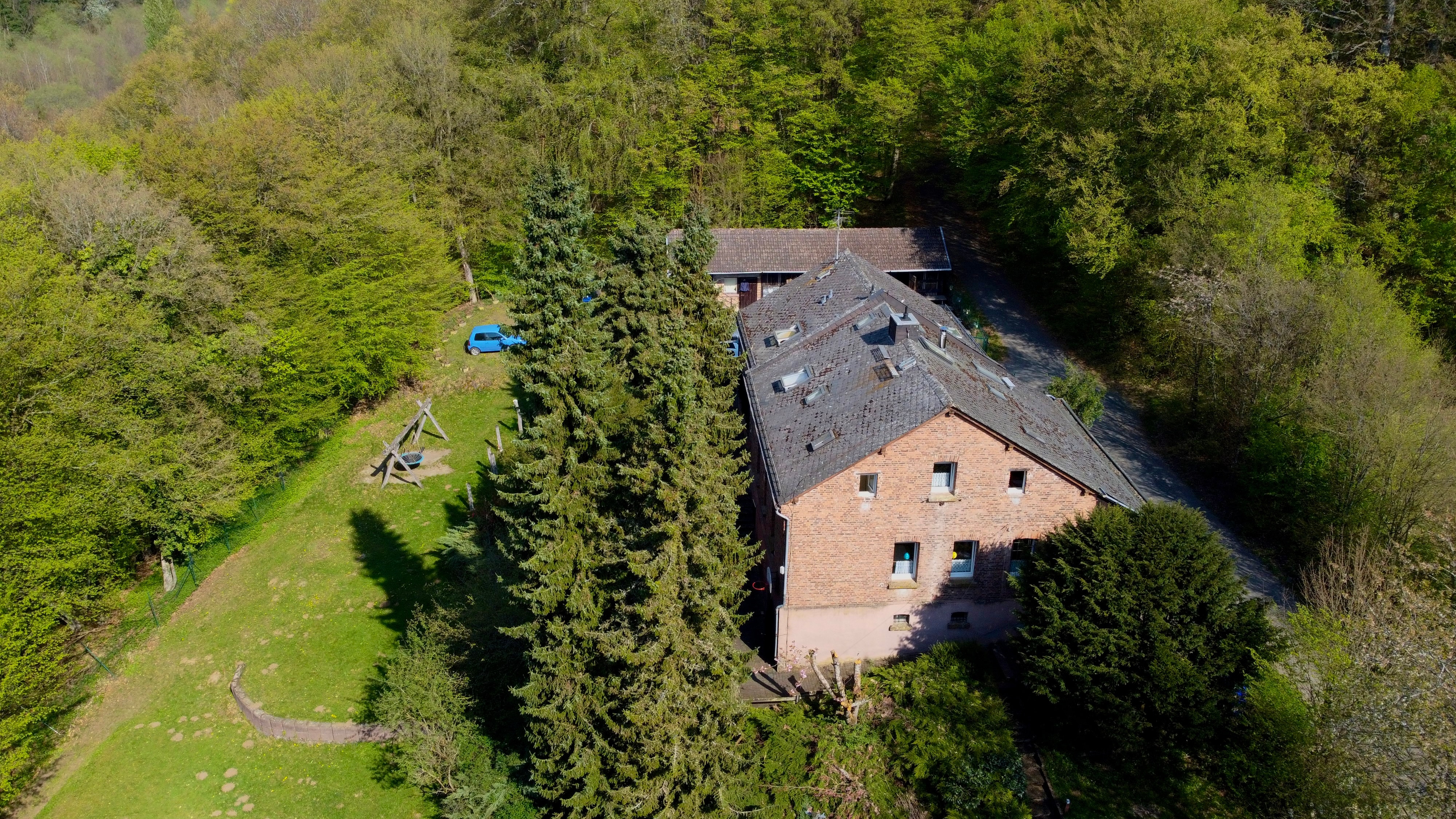 Drohnenaufnahme des Freizeitheims Forsthaus am Dünsberg von oben, eingebettet in dichten Mischwald.